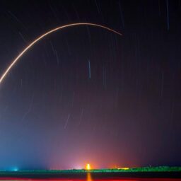 A night sky with stars streaking in the background and a streak of a rocket trailing in a large arc.